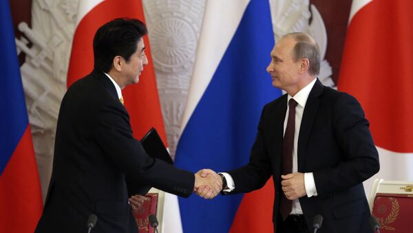 Japanese Prime Minister Shinzo Abe (L) shakes hands with Russian President Vladimir Putin - Sputnik International