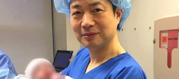 Dr. John Zhang of the Hope Fertility Center in New York holding the first 'three person baby' born using the new method - Sputnik International