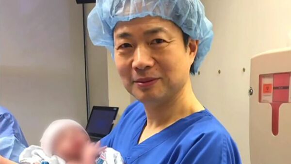 Dr. John Zhang of the Hope Fertility Center in New York holding the first 'three person baby' born using the new method - Sputnik International