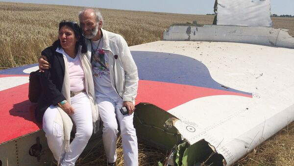 Jerzy Dyczynski and Angela Rudhart-Dyczynski whose daughter, 25-year-old Fatima, was a passenger on Malaysia Airlines flight MH17, sit on part of the wreckage of the crashed aircraft in Hrabove, Ukraine, Saturday, July 26, 2014 - Sputnik International