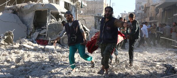 Syrian volunteers carry an injured person on a stretcher following Syrian government forces airstrikes on the rebel held neighbourhood of Heluk in Aleppo, on September 30, 2016 - Sputnik International