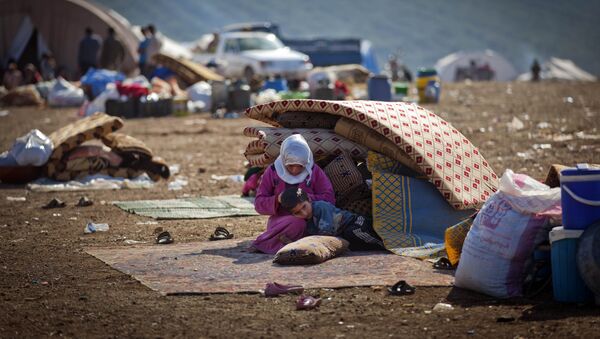 A Syrian family who fled from the violence in their village, sit next to their belongings at a displaced camp, in the Syrian village of Atma, near the Turkish border with Syria. - Sputnik International