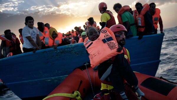 A child from African origin is rescued from a distressed vessel by a member of Proactiva Open Arms NGO in the mediteranean sea some 20 nautical miles north of Libya on October 3, 2016 - Sputnik International