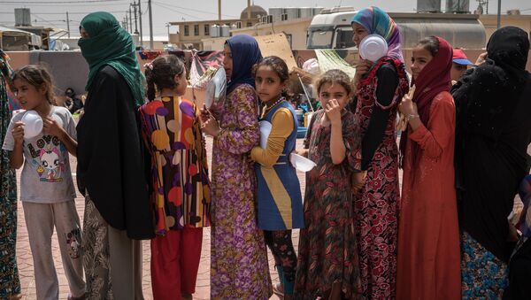 In this Aug. 7, 2016 file photo, women and children stand in line to receive a portion of food at Dibaga camp for internally displaced civilians in Iraq - Sputnik International