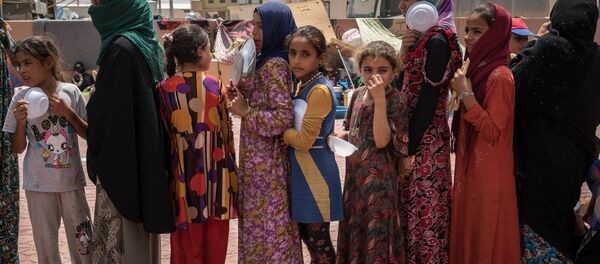 In this Aug. 7, 2016 file photo, women and children stand in line to receive a portion of food at Dibaga camp for internally displaced civilians in Iraq - Sputnik International