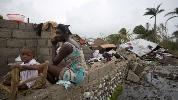 Victor Farah and her daughter sit in the ruins of their home destroyed by Hurricane Matthew in Les Cayes, Haiti, Thursday, Oct. 6, 2016. Two days after the storm rampaged across the country's remote southwestern peninsula, authorities and aid workers still lack a clear picture of what they fear is the country's biggest disaster in years. - Sputnik International
