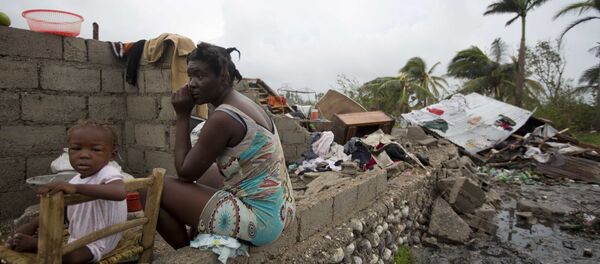 Victor Farah and her daughter sit in the ruins of their home destroyed by Hurricane Matthew in Les Cayes, Haiti, Thursday, Oct. 6, 2016. Two days after the storm rampaged across the country's remote southwestern peninsula, authorities and aid workers still lack a clear picture of what they fear is the country's biggest disaster in years. Victor Farah and her daughter sit in the ruins of their home destroyed by Hurricane Matthew in Les Cayes, Haiti, Thursday, Oct. 6, 2016. Two days after the storm rampaged across the country's remote southwestern peninsula, authorities and aid workers still lack a clear picture of what they fear is the country's biggest disaster in years. - Sputnik International