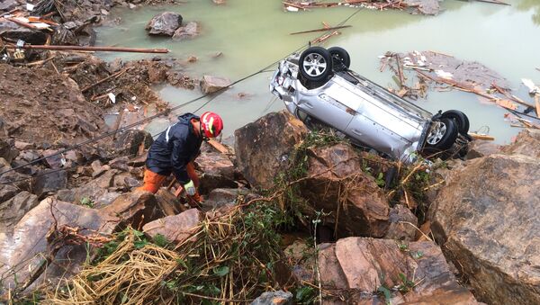 A rescue worker is seen next to an overturned car at the site of a landslide caused by heavy rains brought by Typhoon Megi, in Sucun Village, Lishui, Zhejiang province, China, September 29, 2016 - Sputnik International