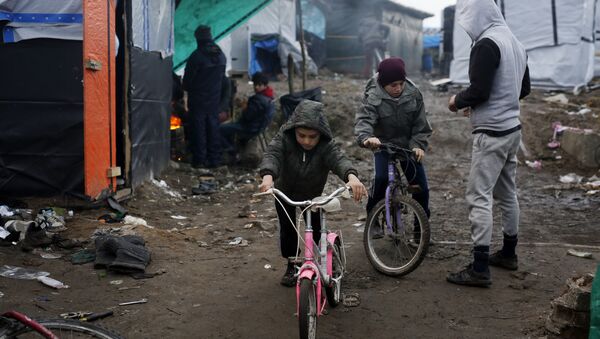 Afghan children ride their bicycles in a makeshift migrants camp near Calais, France, Thursday Feb. 25, 2016 - Sputnik International