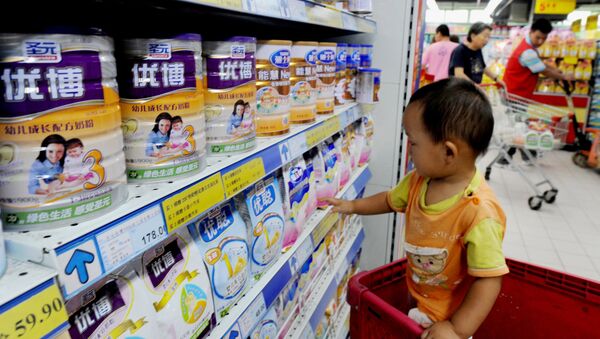A Chinese baby plays beside tins of milk powder made by NASDAQ-listed Synutra (L-1) on sale at a supermarket in Beijing on August 9, 2010 - Sputnik International