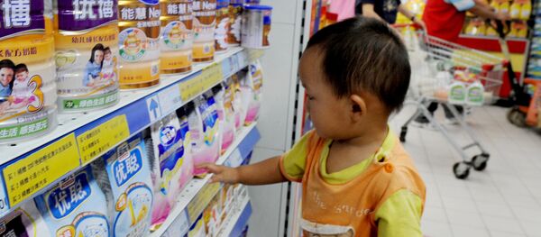 A Chinese baby plays beside tins of milk powder made by NASDAQ-listed Synutra (L-1) on sale at a supermarket in Beijing on August 9, 2010 - Sputnik International