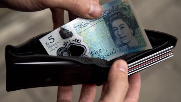 In this posed photograph a person is pictured holding a wallet containing a £5 (five pound) note in London on October 7, 2016.  - Sputnik International