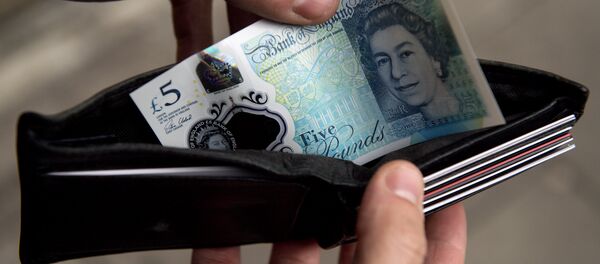 In this posed photograph a person is pictured holding a wallet containing a £5 (five pound) note in London on October 7, 2016. In this posed photograph a person is pictured holding a wallet containing a £5 (five pound) note in London on October 7, 2016. - Sputnik International