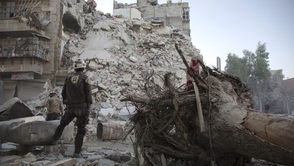 A member of the Syrian Civil Defence, known as the White Helmets, stands amid the rubble of a destroyed building during a rescue operation following reported air strikes in the rebel-held Qatarji neighbourhood of the northern city of Aleppo, on October 17, 2016 - Sputnik International
