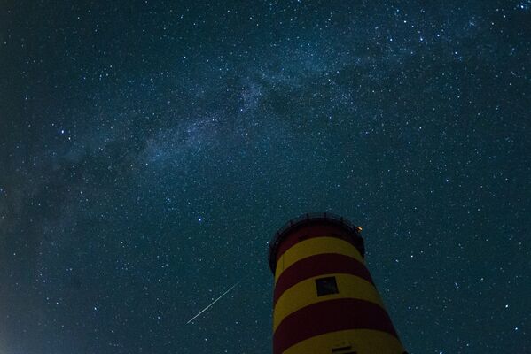 A falling star crosses the night sky behind the lighthouse in Pilsum, northwestern Germany. - Sputnik International