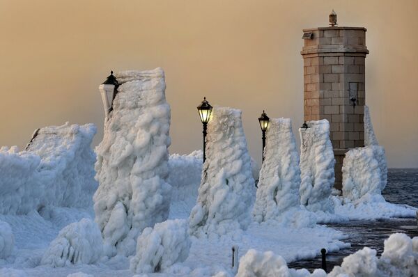The harbour breakwater with lighthouse and lampposts is covered with heavy ice in the central Adriatic Croatian port of Senj, some 200 kilometres from Zagreb, as the sun sets on February 8, 2012. - Sputnik International