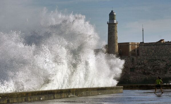 A youngster (R) stands in front of a huge wave breaking in Havana's seafront. - Sputnik International