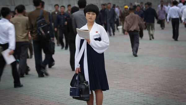 A North Korean student pauses to study as other people make their way to work during morning rush hour - Sputnik International