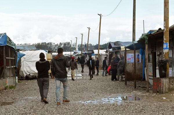 Migrants walks through the Jungle migrant camp in Calais, northern France, on October 22, 2016 - Sputnik International