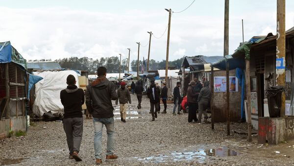 Migrants walks through the Jungle migrant camp in Calais, northern France, on October 22, 2016 - Sputnik International