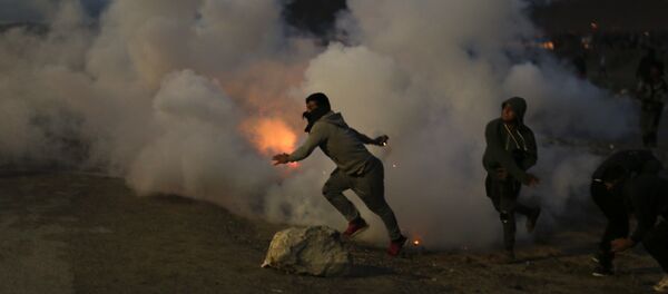 Demonstrators throw back tear gas canisters to French riot police officers during clashes in a makeshift migrant camp known as the jungle near Calais, northern France, on Saturday, Oct. 22, 2016 - Sputnik International