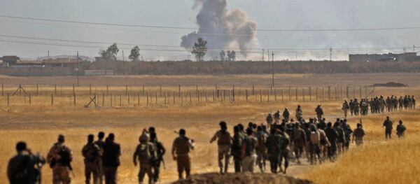Smoke billows from an area near the Iraqi town of Nawaran, some 10km north east of Mosul, as Iraqi Kurdish Peshmerga fighters march down a dirt road on October 20, 2016, during the ongoing operation to retake the city from the Islamic State (IS) group - Sputnik International