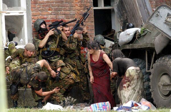 A Russian special police soldier (L) carries an injured colleague as two soldiers and two women take cover behind the APC during the Beslan School rescue operation, northern Ossetia, September 3, 2004. - Sputnik International