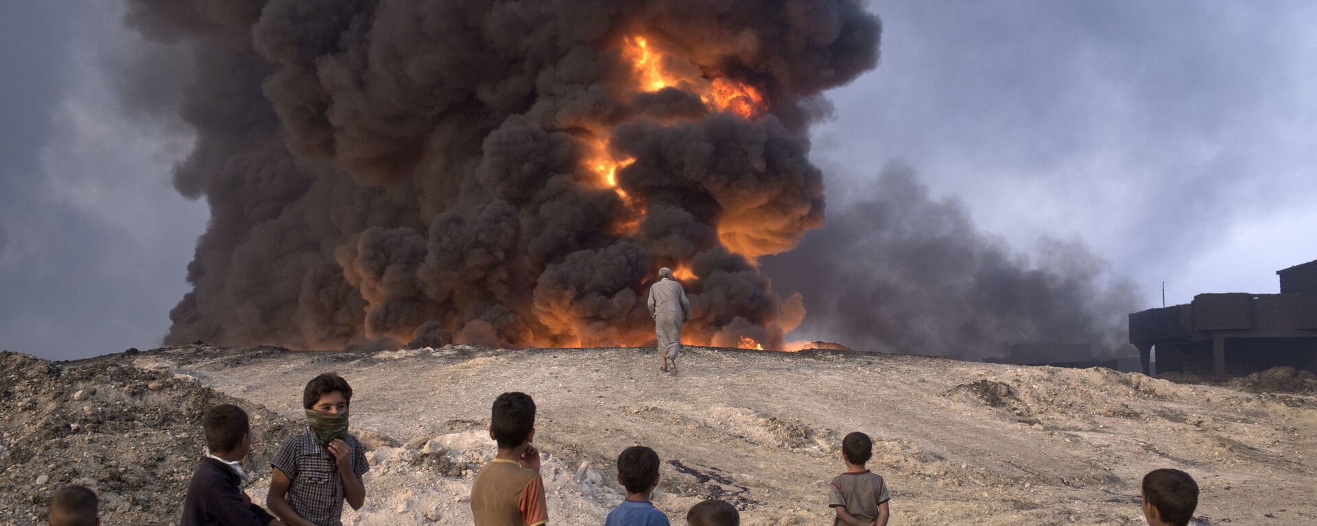 FILE -- In this Sunday, Oct. 23, 2016 file photo, people watch a burning oil well in Qayyarah, about 31 miles (50 km) south of Mosul, Iraq - Sputnik International, 1920, 24.10.2023