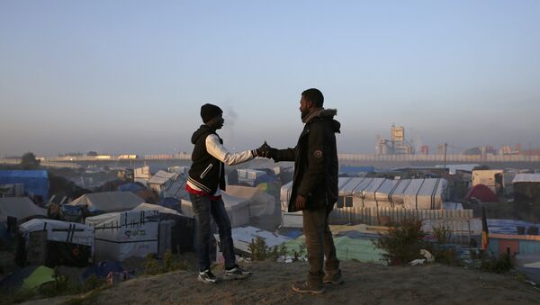 Migrants shake hands as they stand on a high point near tents and makeshift shelters on the second day of their evacuation and transfer to reception centers in France, during the dismantlement of the camp called the Jungle in Calais, France, October 25, 2016 - Sputnik International