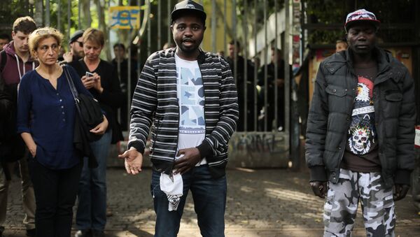 Sudanese refugees, who said their names are Adam, center, and Anour, right, speak to media in front of the entrance of the occupied Gerhart Hauptmann School in Berlin, Germany, Friday, June 27, 2014 - Sputnik International