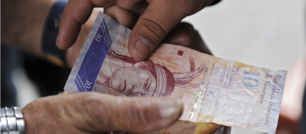 A man receives Venezuelan currency bills in Caracas on November 30, 2011. - Sputnik International