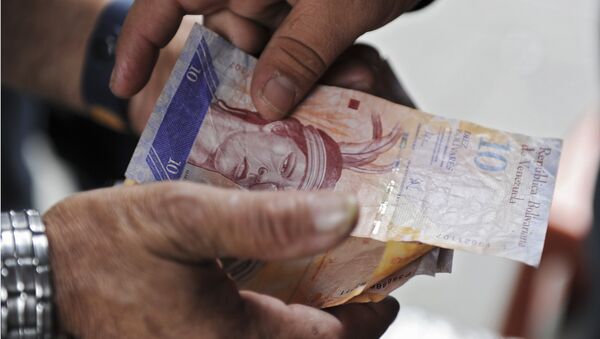 A man receives Venezuelan currency bills in Caracas on November 30, 2011. - Sputnik International