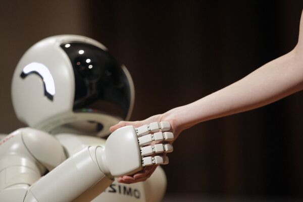 Honda Motors' humanoid robot ASIMO (Advanced Step in Innovative Mobility) shakes hands with an assistant as it demonstrates its skills, in Belgrade, Serbia, on September 24, 2012. - Sputnik International