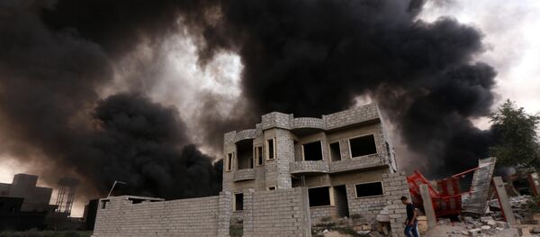 An Iraqi man walks near smoke billowing An Iraqi man walks near smoke billowing - Sputnik International