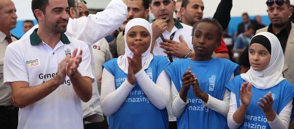 Former Barcelona football player Xavi Hernandez (L), who currently plays for Al-Sadd in the Qatar Stars League, claps during a football training as he visits the al-Baqaa Palestinian refugee camp near Amman on September 29, 2016. Former Barcelona football player Xavi Hernandez (L), who currently plays for Al-Sadd in the Qatar Stars League, claps during a football training as he visits the al-Baqaa Palestinian refugee camp near Amman on September 29, 2016. - Sputnik International