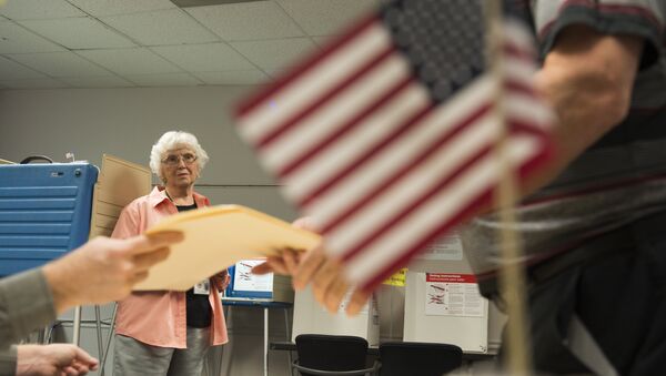 An election official watches as a man takes a ballot at an in-person absentee voting station in Fairfax, Virginia on October 12, 2016 - Sputnik International