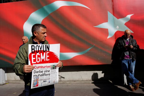 A supporter of Cumhuriyet newspaper, an opposition secularist daily, holds a placard and the latest copy during a protest in front of its headquarters in Istanbul, Turkey, October 31, 2016. The placard reads, Don't bow down. A supporter of Cumhuriyet newspaper, an opposition secularist daily, holds a placard and the latest copy during a protest in front of its headquarters in Istanbul, Turkey, October 31, 2016. The placard reads, Don't bow down. - Sputnik International