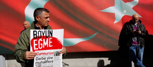 A supporter of Cumhuriyet newspaper, an opposition secularist daily, holds a placard and the latest copy during a protest in front of its headquarters in Istanbul, Turkey, October 31, 2016. The placard reads, Don't bow down. A supporter of Cumhuriyet newspaper, an opposition secularist daily, holds a placard and the latest copy during a protest in front of its headquarters in Istanbul, Turkey, October 31, 2016. The placard reads, Don't bow down. - Sputnik International
