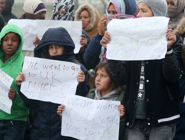 Young migrants pose with posters reading 'We want to go faster to UK' and 'We have family waiting for us' at the Jungle migrant camp in Calais, northern France, on October 26, 2016. Young migrants pose with posters reading 'We want to go faster to UK' and 'We have family waiting for us' at the Jungle migrant camp in Calais, northern France, on October 26, 2016. - Sputnik International