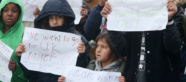 Young migrants pose with posters reading 'We want to go faster to UK' and 'We have family waiting for us' at the Jungle migrant camp in Calais, northern France, on October 26, 2016. Young migrants pose with posters reading 'We want to go faster to UK' and 'We have family waiting for us' at the Jungle migrant camp in Calais, northern France, on October 26, 2016. - Sputnik International