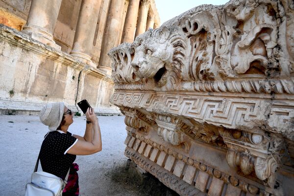 A visitor takes pictures of a bas-relief with heads of lions from the roof of the Temple of Jupiter in a temple complex of Baalbek, Lebanon - Sputnik International