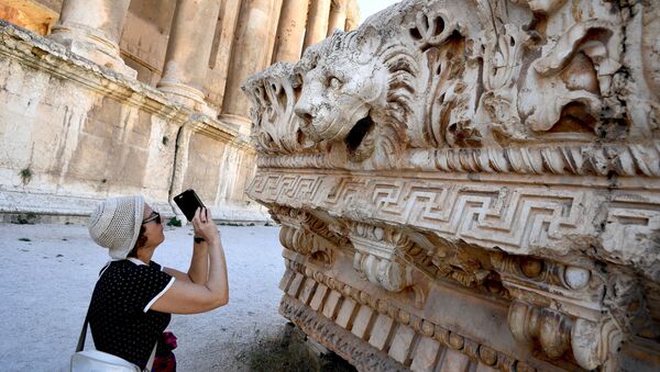 A visitor takes pictures of a bas-relief with heads of lions from the roof of the Temple of Jupiter in a temple complex of Baalbek, Lebanon - Sputnik International