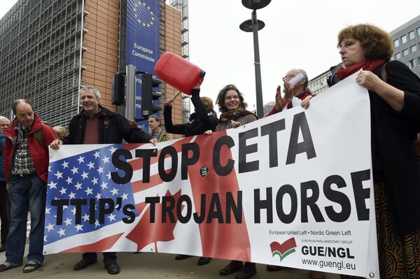People hold a banner reading Stop EU-Canada Comprehensive Economic and Trade Agreement (CETA), Transatlantic Trade and Investment Partnership (TTIP)'s trojan horse during a protest against the CETA at European Union Commission headquarters in Brussels on October 27, 2016 People hold a banner reading Stop EU-Canada Comprehensive Economic and Trade Agreement (CETA), Transatlantic Trade and Investment Partnership (TTIP)'s trojan horse during a protest against the CETA at European Union Commission headquarters in Brussels on October 27, 2016 - Sputnik International