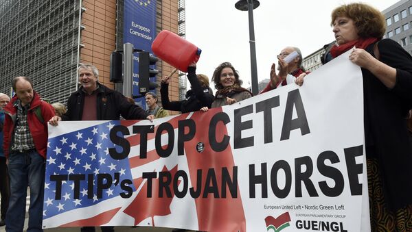 People hold a banner reading Stop EU-Canada Comprehensive Economic and Trade Agreement (CETA), Transatlantic Trade and Investment Partnership (TTIP)'s trojan horse during a protest against the CETA at European Union Commission headquarters in Brussels on October 27, 2016 - Sputnik International