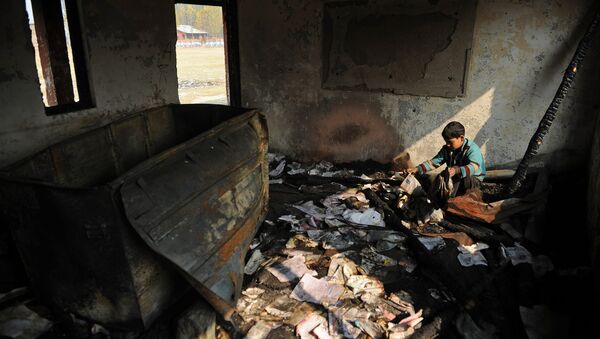 A Kashmiri student looks at damaged property at a partially burnt government high school in Goripora, on the outskirts of Srinagar on November 2, 2016 - Sputnik International