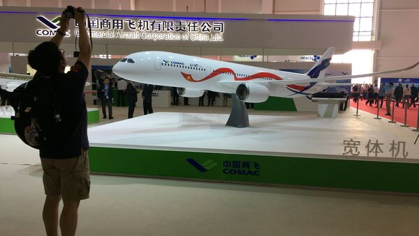 A man takes picture of the model of a widebody jet, which is planned to be developed by Commercial Aircraft Corporation of China (COMAC) and Russia's United Aircraft Corporation (UAC) at an air show, the China International Aviation and Aerospace Exhibition, in Zhuhai, Guangdong Province, China, November 2, 2016 - Sputnik International
