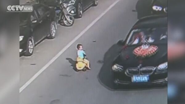 Kid drives toy car through traffic on busy road - Sputnik International