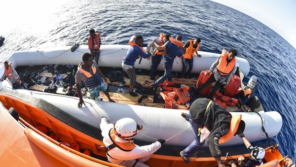 Men evacuate a rubber boat with the help of the crew of the Topaz Responder ship run by Maltese NGO Moas and the Italian Red Cross during a rescue operation of Migrants and refugees on November 3, 2016, off the Libyan coast in the Mediterranean Sea - Sputnik International