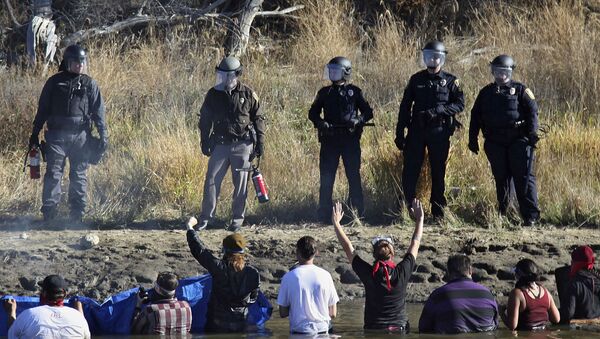 Dozens of protestors demonstrating against the expansion of the Dakota Access Pipeline wade in cold creek waters confronting local police, as remnants of pepper spray waft over the crowd near Cannon Ball, N.D., Wednesday, Nov. 2, 2016. - Sputnik International