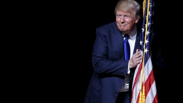 U.S. Republican presidential candidate Donald Trump hugs a U.S. flag as he takes the stage for a campaign town hall meeting in Derry, New Hampshire August 19, 2015 - Sputnik International